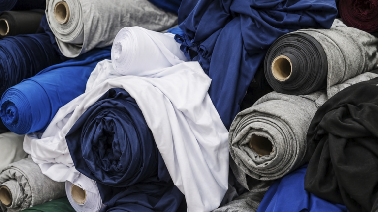 Uniforme escolar branco sobre tecido claro, representando a escolha de tecido para produção de uniforme para volta às aulas.
